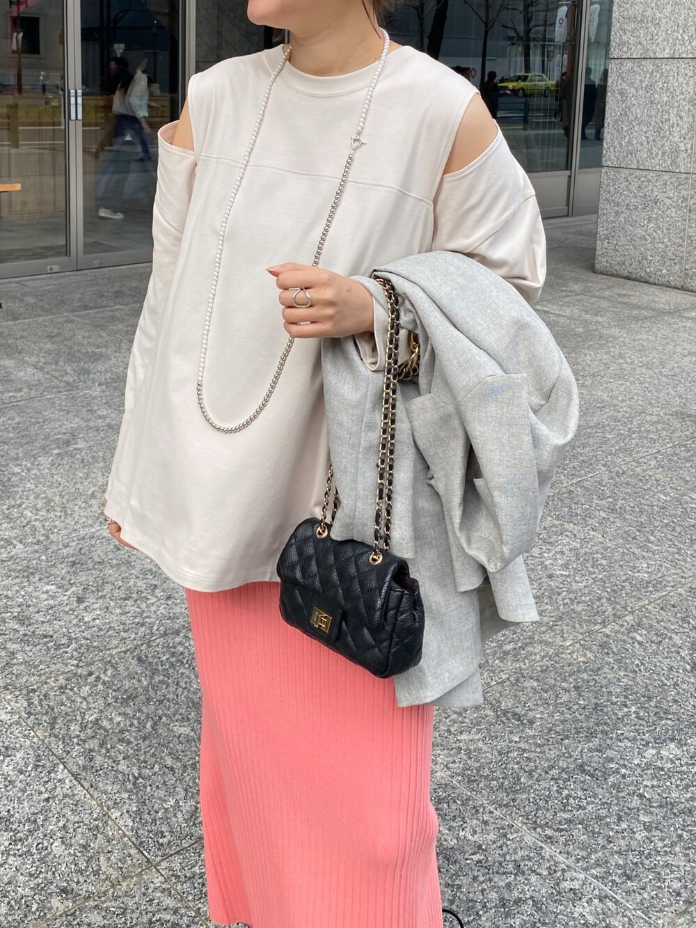 ピンク系のスカート、グレー系のテーラードジャケット、ブルー系のショルダーバッグを着用したレディースの冬コーディネートの4枚目の写真