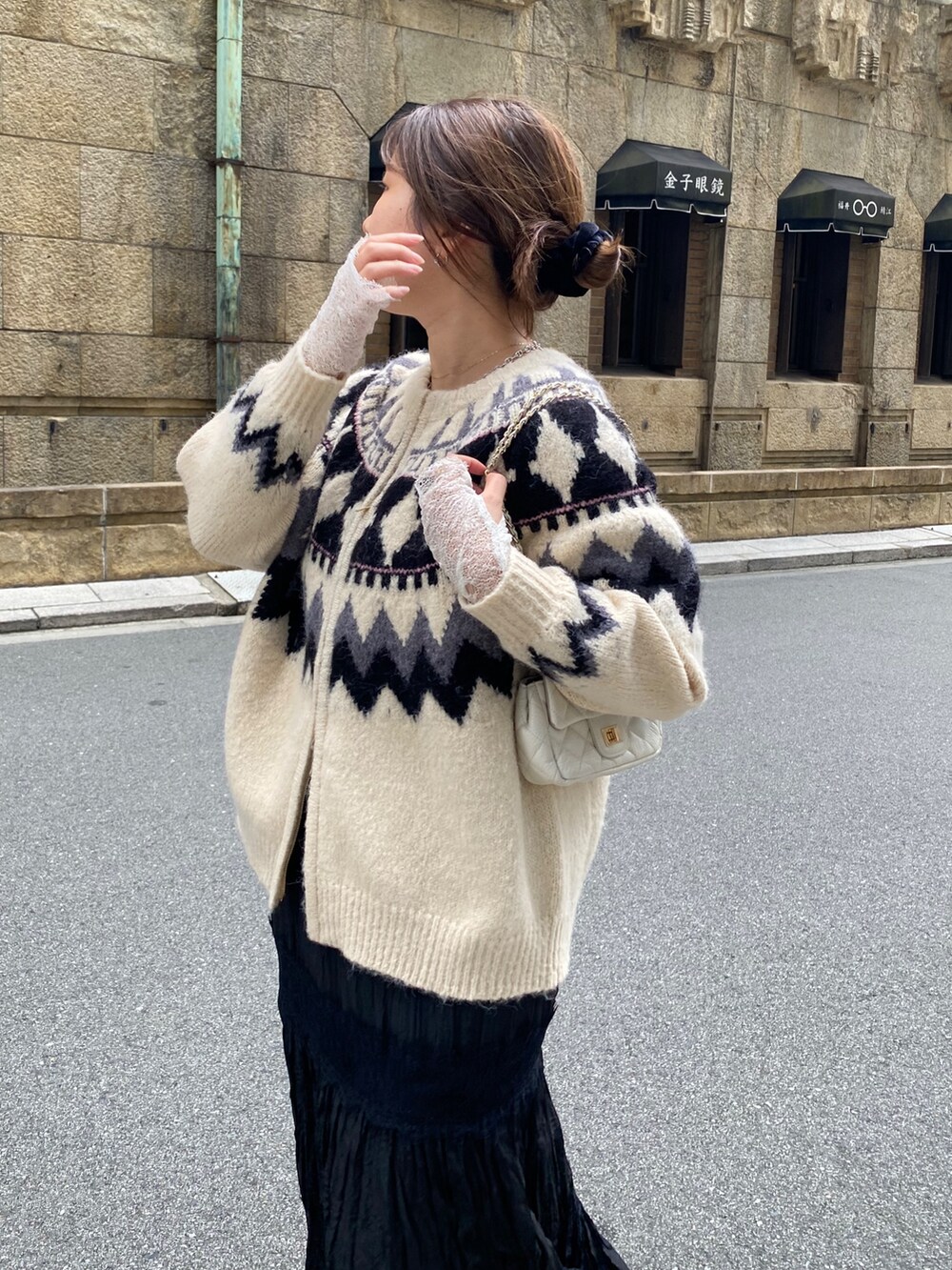 ホワイト系のカーディガン/ボレロ、ホワイト系のTシャツ/カットソー、ブラック系のスカートを着用したレディースの冬コーディネートの2枚目の写真