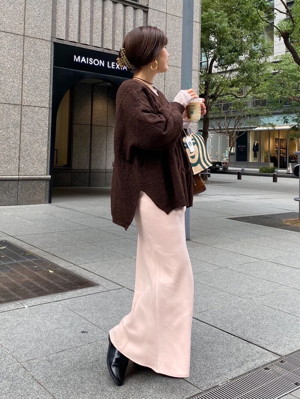 ブラウン系のニット/セーター、ピンク系のスカート、ブラック系のブーツを着用したレディースの冬コーディネートの2枚目の写真