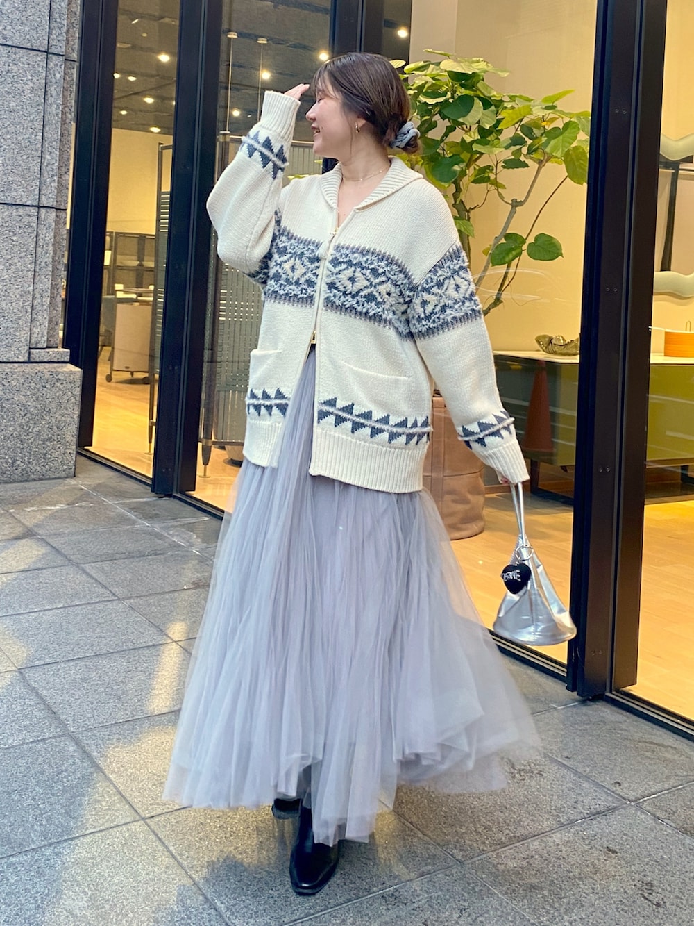 ホワイト系のニット/セーター、グレー系のスカート、シルバー系のショルダーバッグを着用したレディースの冬コーディネートの2枚目の写真