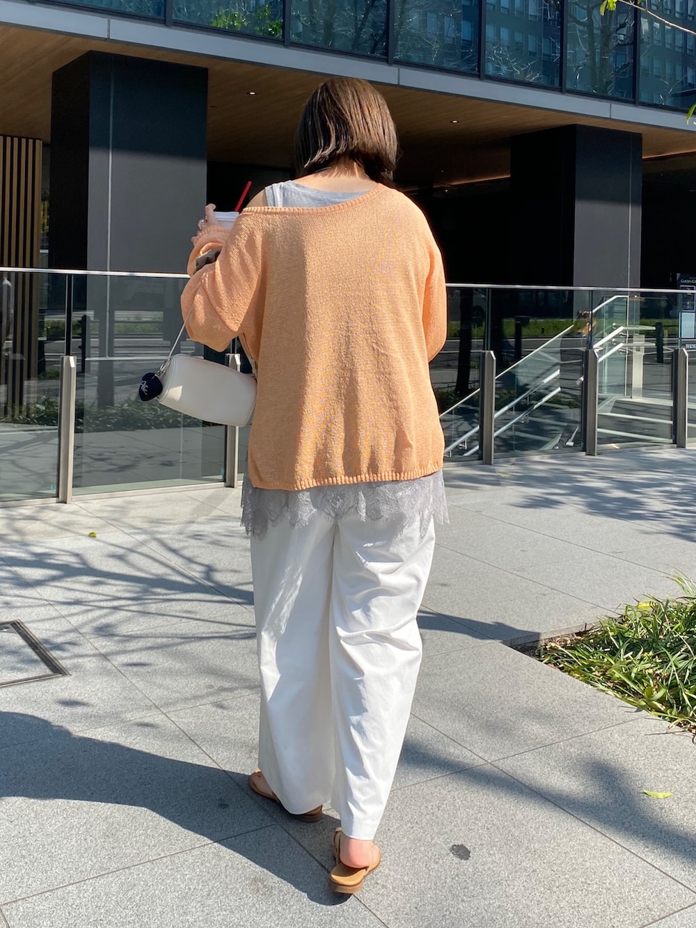 オレンジ系のニット/セーター、グレー系のTシャツ/カットソー、ホワイト系のその他パンツを着用したレディースの春コーディネートの6枚目の写真