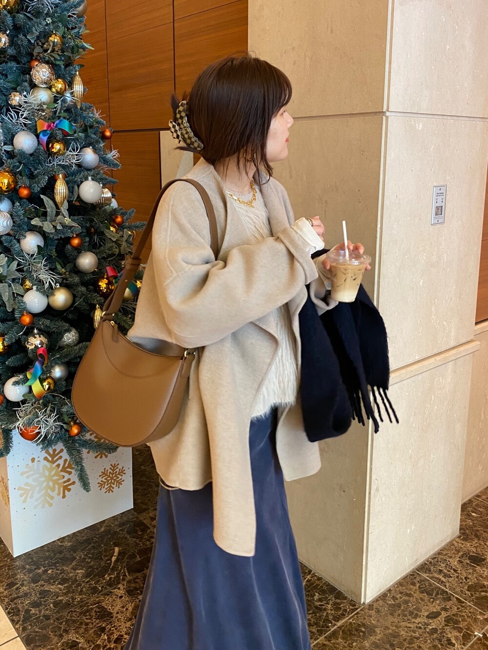イエロー系のその他アウター、ホワイト系のニット/セーター、ホワイト系のスカートを着用したレディースの冬コーディネートの9枚目の写真