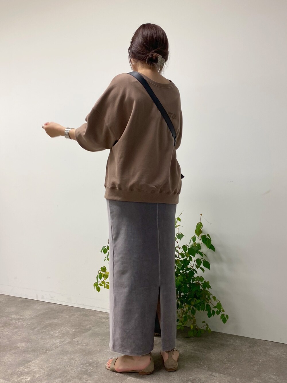 グレー系のスカート、ブラウン系のスウェット、ブラック系のバッグを着用したレディースの夏コーディネートの3枚目の写真