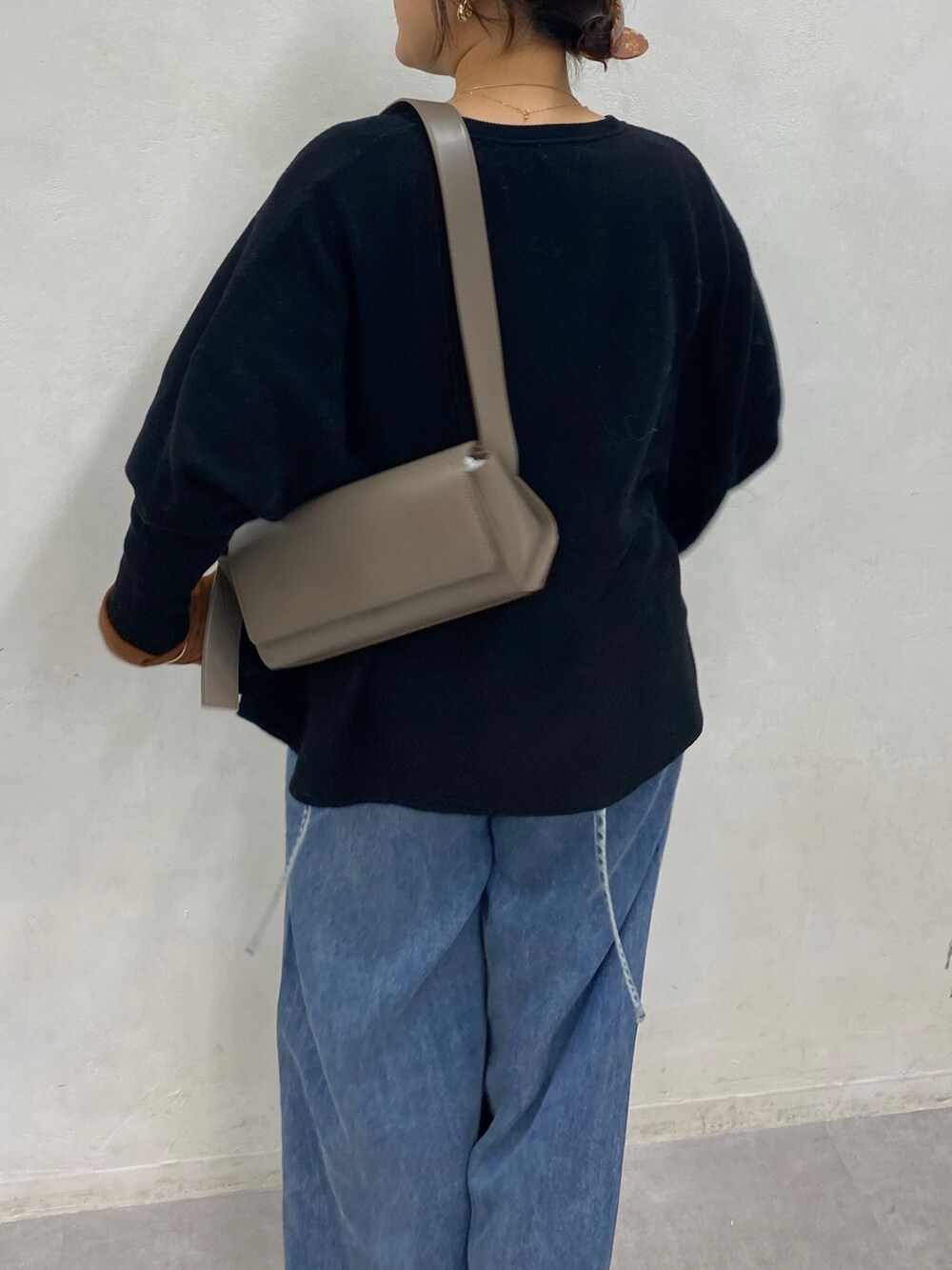 ブラック系のニット/セーター、ブルー系のデニムパンツ、ブラウン系のTシャツ/カットソーを着用したレディースの冬コーディネートの7枚目の写真