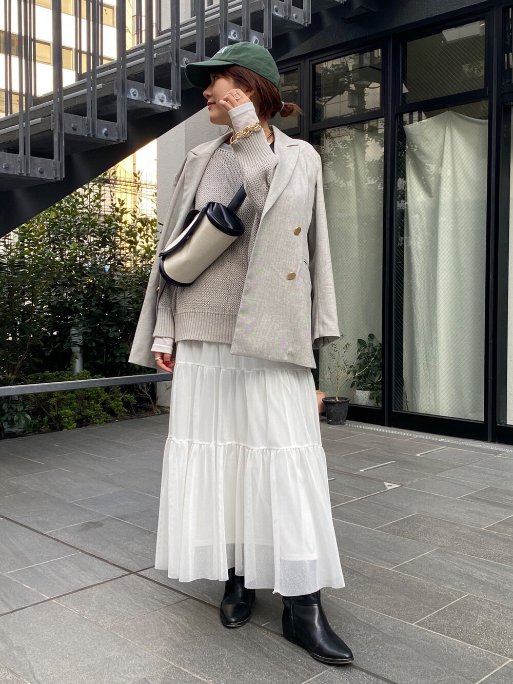 ホワイト系のニット/セーター、グレー系のテーラードジャケット、グリーン系のスカートを着用したレディースの春コーディネートの5枚目の写真