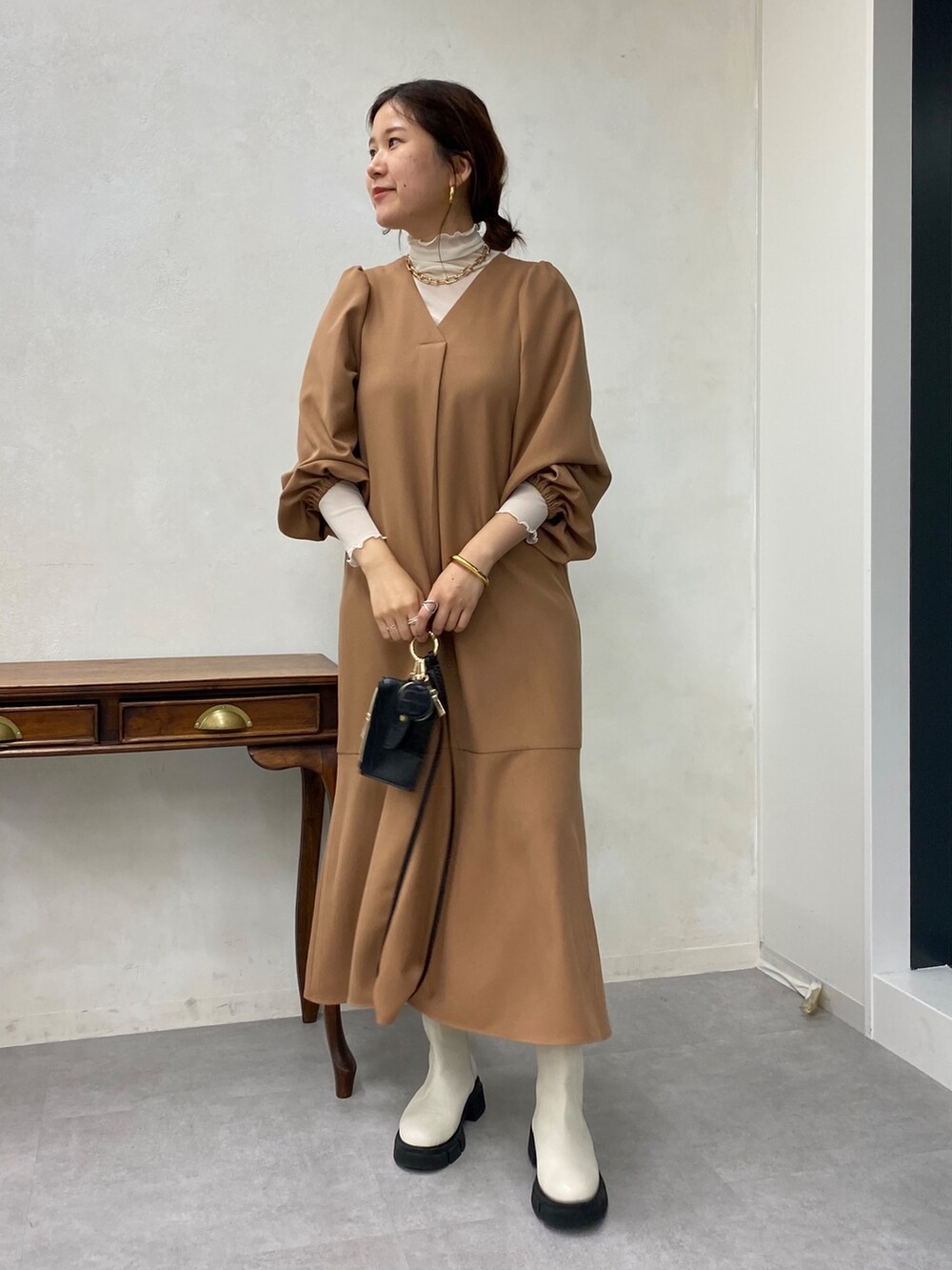 ベージュ系のワンピース、ホワイト系のTシャツ/カットソー、ホワイト系のブーツを着用したレディースの秋コーディネートの5枚目の写真