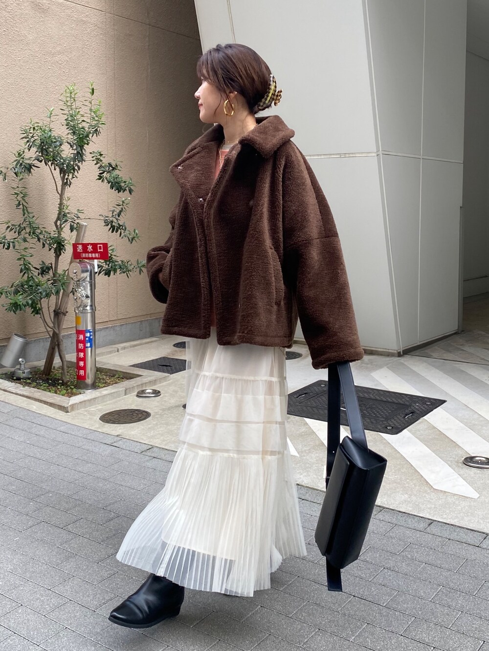 ブラウン系のその他アウター、オレンジ系のスウェット、ホワイト系のスカートを着用したレディースの冬コーディネートの8枚目の写真