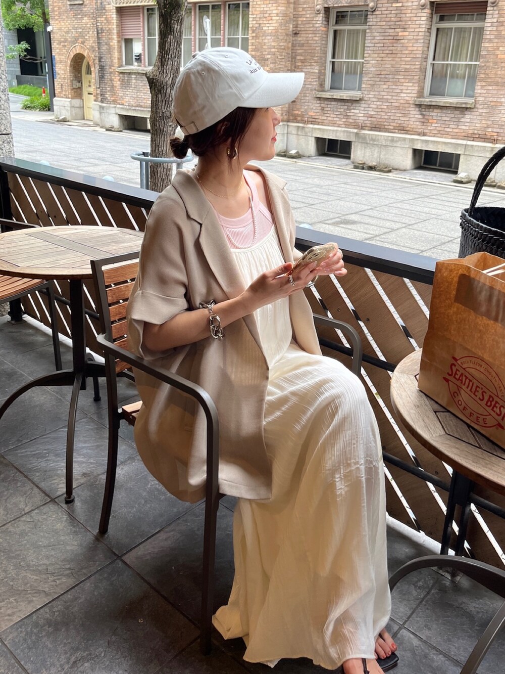 ホワイト系のワンピース、ベージュ系のテーラードジャケット、ホワイト系のキャップを着用したレディースの夏コーディネートの8枚目の写真