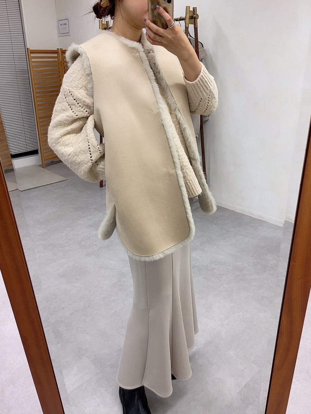 ベージュ系のベスト、ホワイト系のニット/セーター、ベージュ系のスカートを着用したレディースの秋コーディネートの3枚目の写真