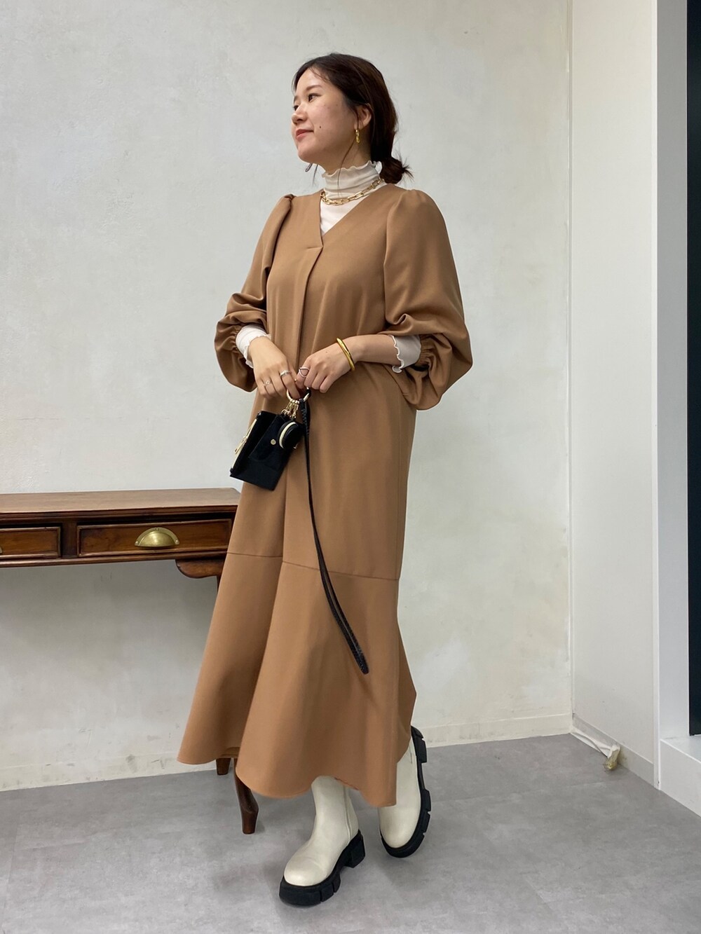 ベージュ系のワンピース、ホワイト系のTシャツ/カットソー、ホワイト系のブーツを着用したレディースの秋コーディネートの3枚目の写真