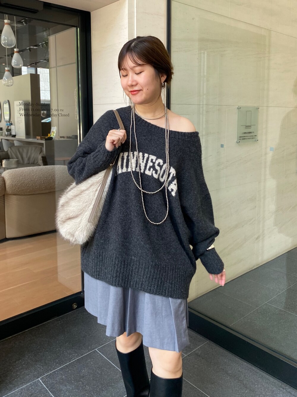 グレー系のニット/セーター、グレー系のスカート、ブラック系のブーツを着用したレディースの秋コーディネートの8枚目の写真