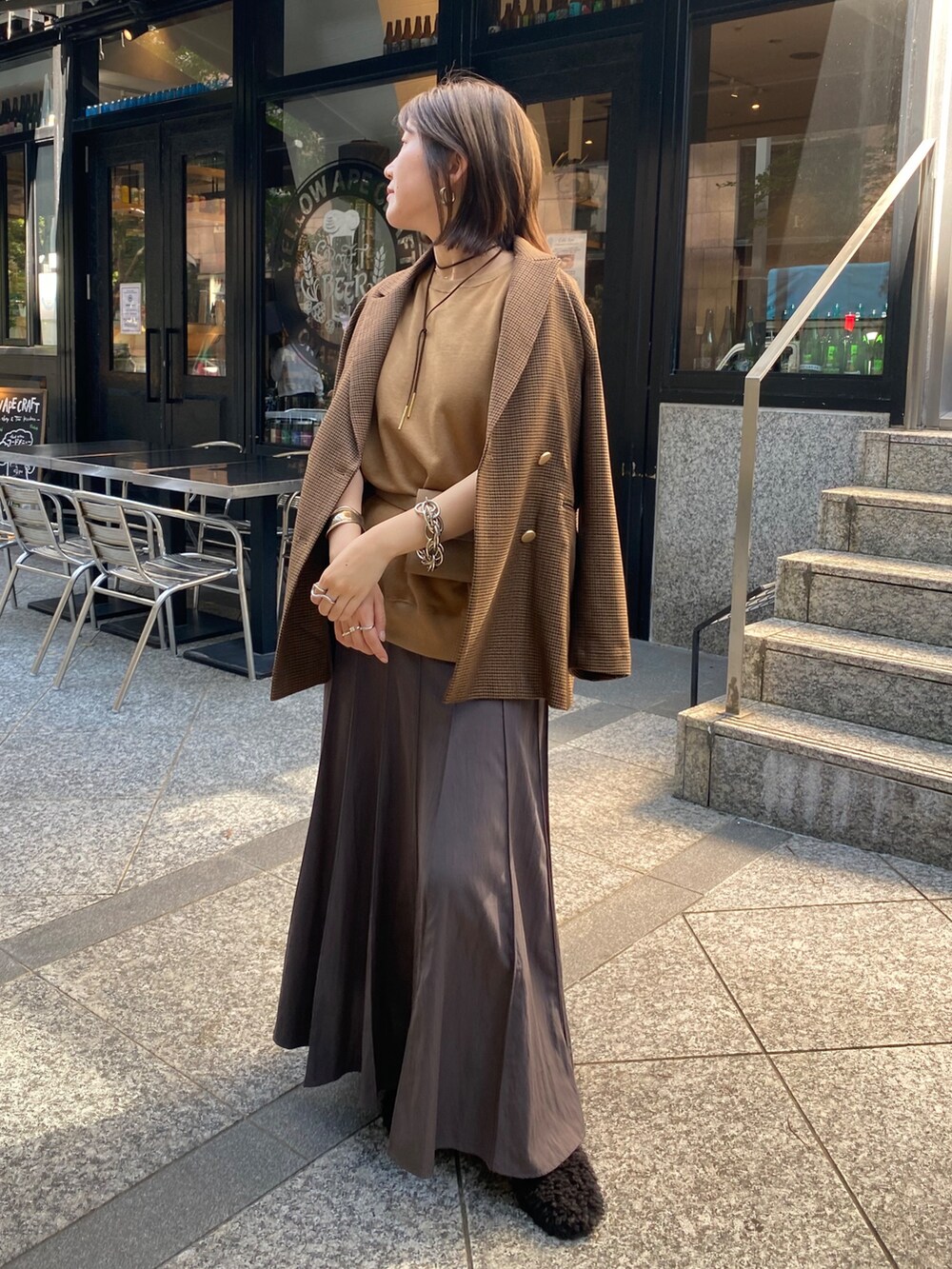 イエロー系のスウェット、グレー系のスカート、ブラウン系のテーラードジャケットを着用したレディースの夏コーディネートの6枚目の写真
