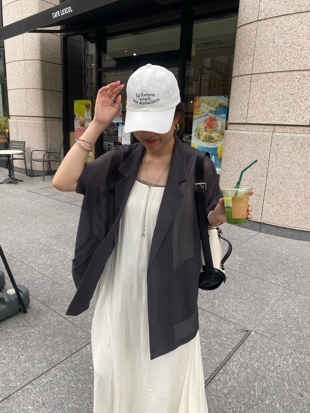 グレー系のテーラードジャケット、ホワイト系のワンピース、ホワイト系のキャップを着用したレディースの夏コーディネートの4枚目の写真