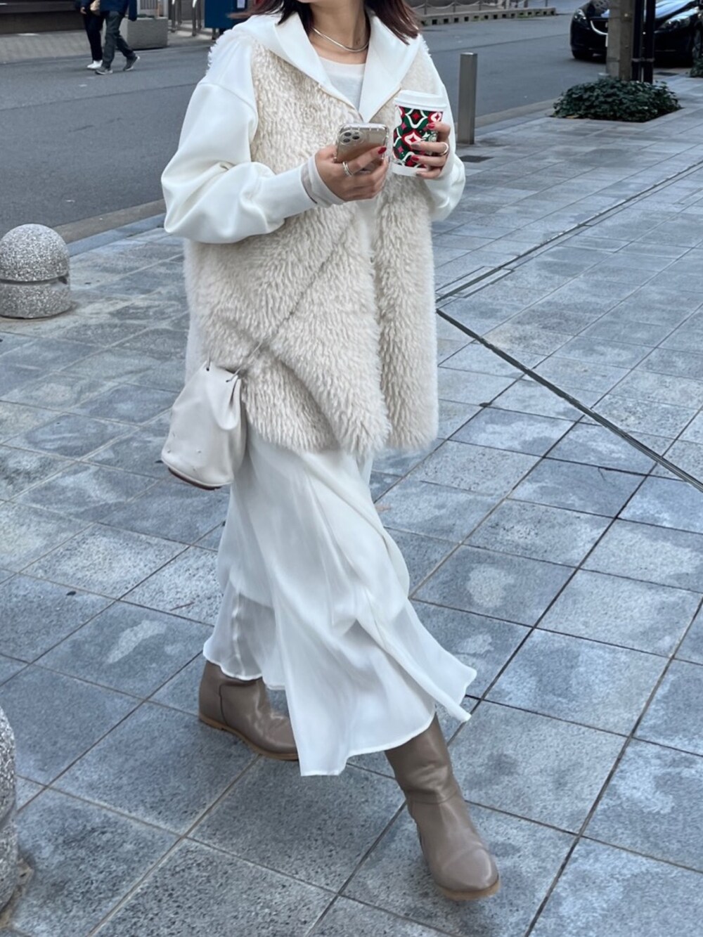 ホワイト系のベスト、ホワイト系のパーカー、ホワイト系のスカートを着用したレディースの冬コーディネートの5枚目の写真