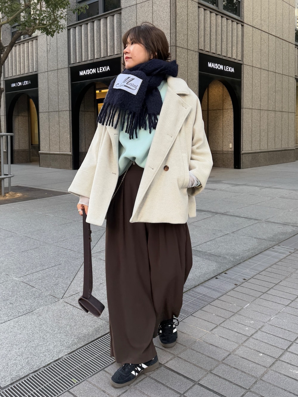 グリーン系のニット/セーター、ブラウン系のスラックス、グレー系のTシャツ/カットソーを着用したレディースの冬コーディネートの6枚目の写真