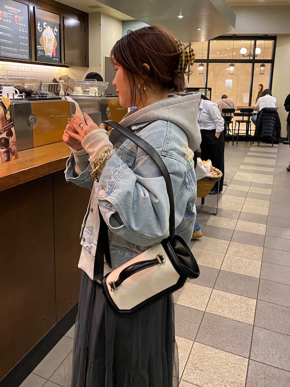 ブルー系のデニムジャケット、グレー系のワンピース、グレー系のパーカーを着用したレディースの春コーディネートの6枚目の写真