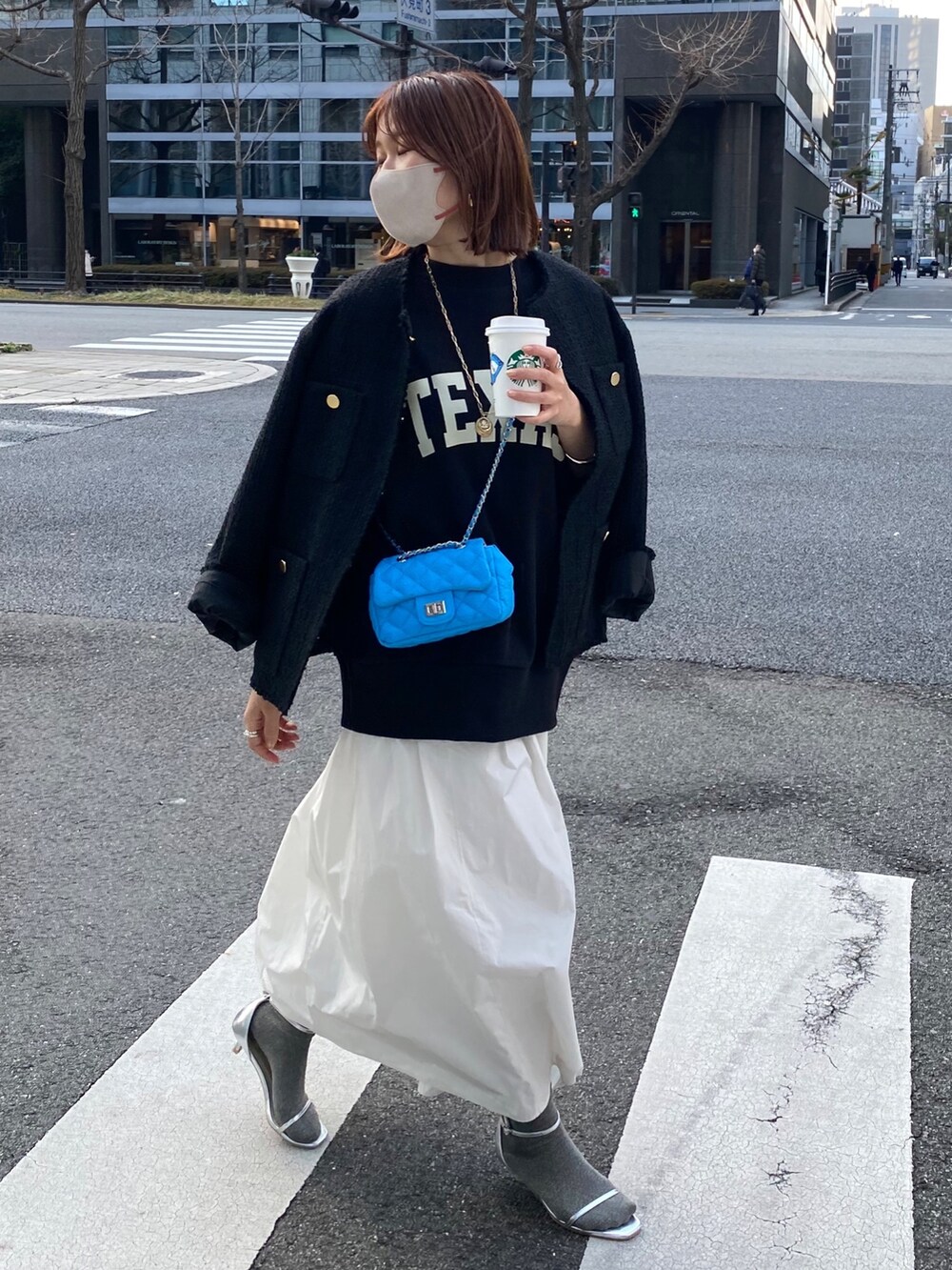 ブラック系のスウェット、ブラック系のノーカラージャケット、ホワイト系のスカートを着用したレディースの春コーディネートの7枚目の写真