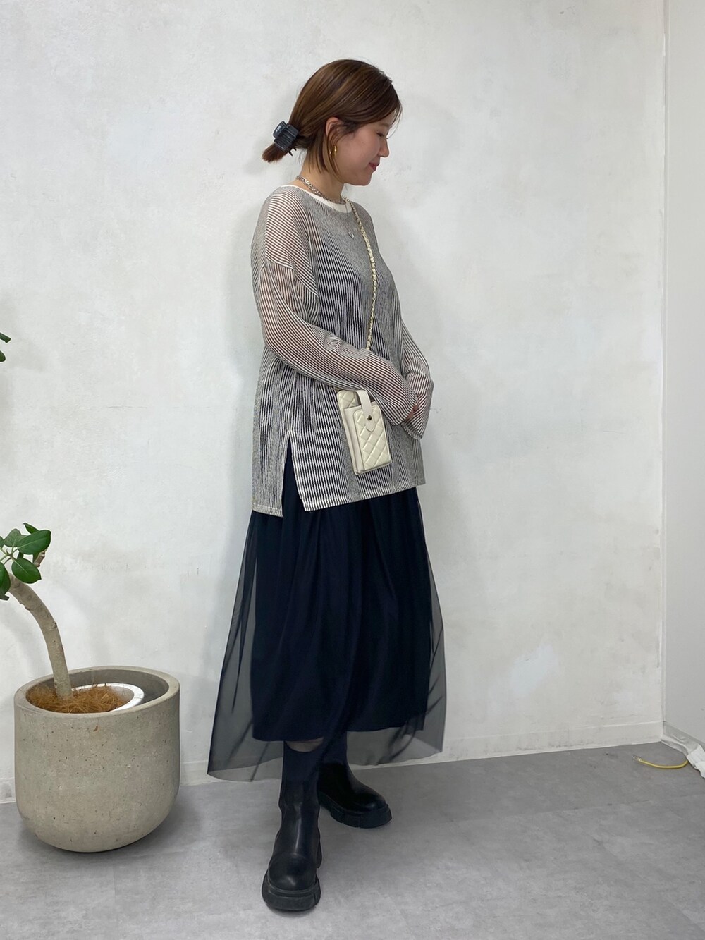 ブラック系のTシャツ/カットソー、ホワイト系のショルダーバッグ、ブラック系のスカートを着用したレディースの冬コーディネートの4枚目の写真