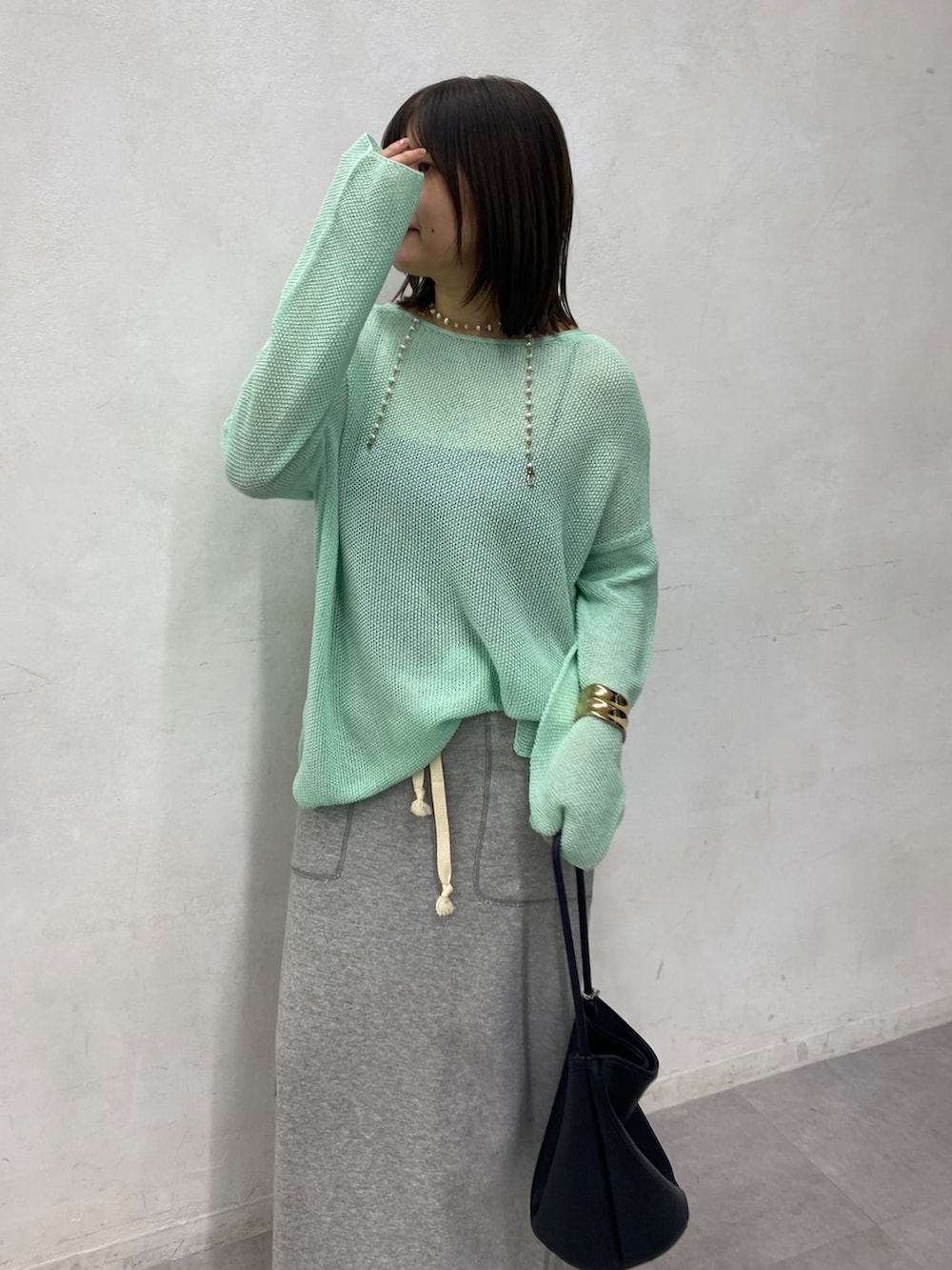 グリーン系のニット/セーター、グレー系のスカートを着用したレディースの春コーディネートの5枚目の写真