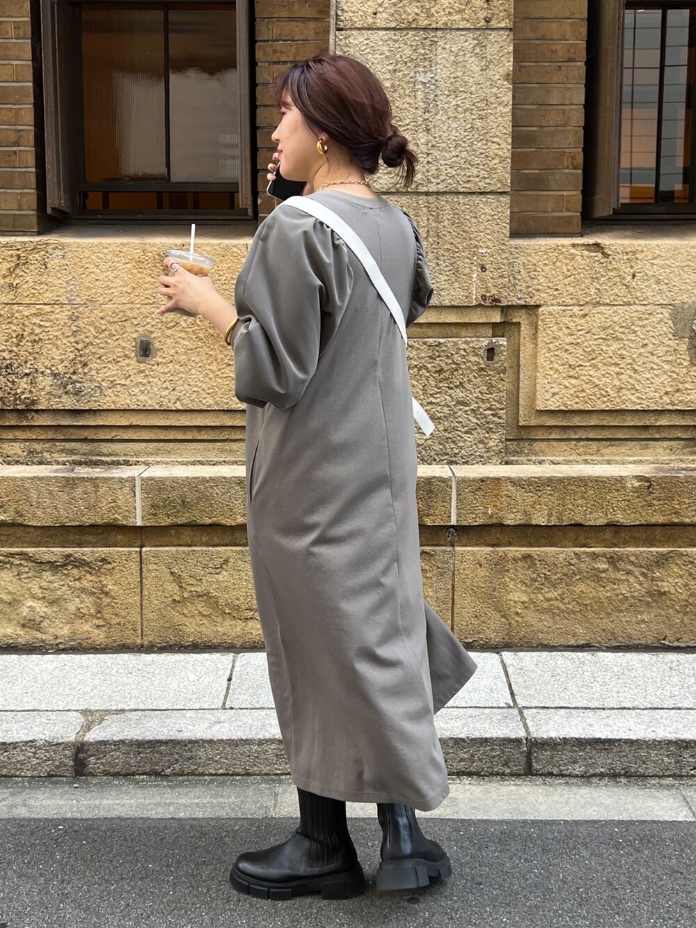 ブラウン系のワンピース、ホワイト系のショルダーバッグ、ブラック系のブーツを着用したレディースの秋コーディネートの4枚目の写真