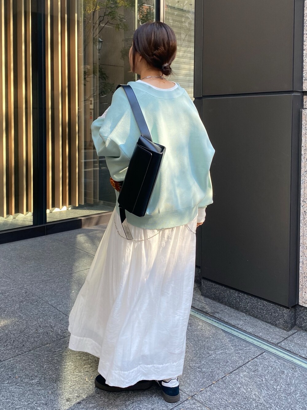 グリーン系のカーディガン/ボレロ、ホワイト系のスカートを着用したレディースの冬コーディネートの2枚目の写真