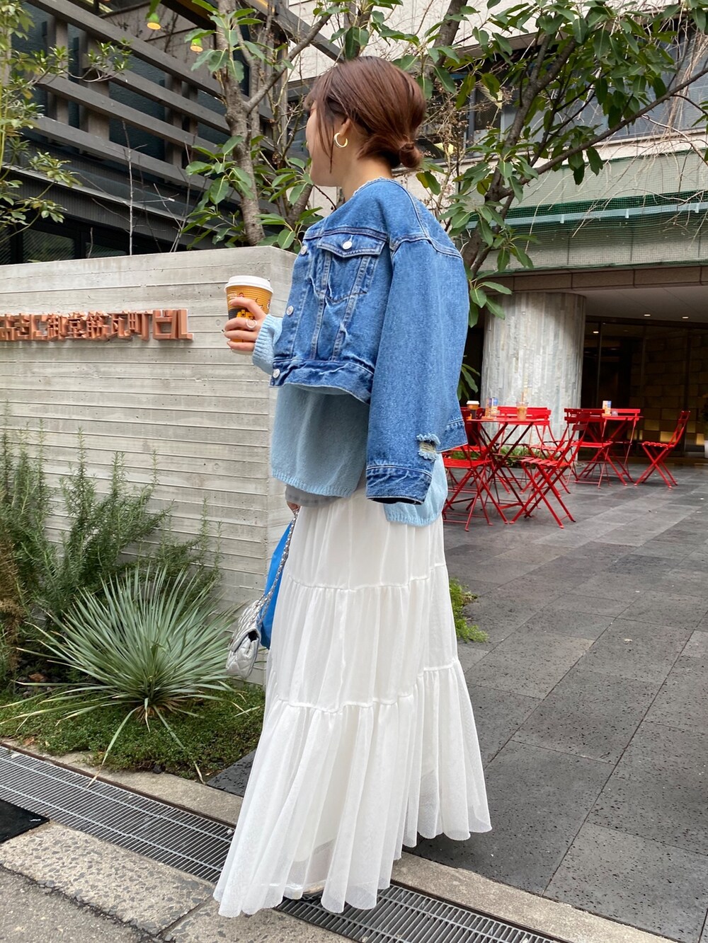 ブルー系のデニムジャケット、グレー系のニット/セーター、ホワイト系のTシャツ/カットソーを着用したレディースの春コーディネートの2枚目の写真