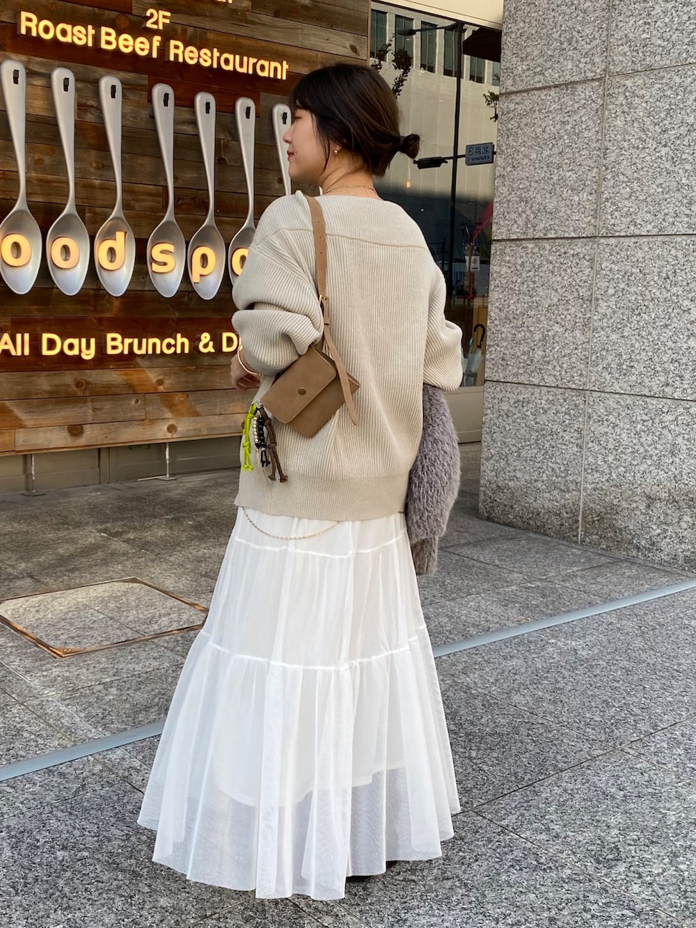 ベージュ系のニット/セーター、ホワイト系のスカート、グレー系のその他アウターを着用したレディースの冬コーディネートの2枚目の写真