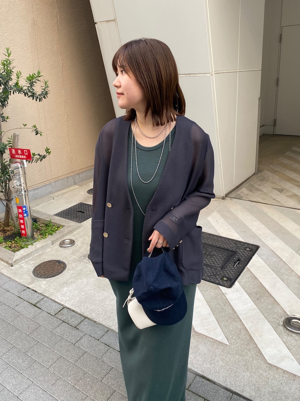 グレー系のテーラードジャケット、グリーン系のワンピースを着用したレディースの春コーディネートの3枚目の写真