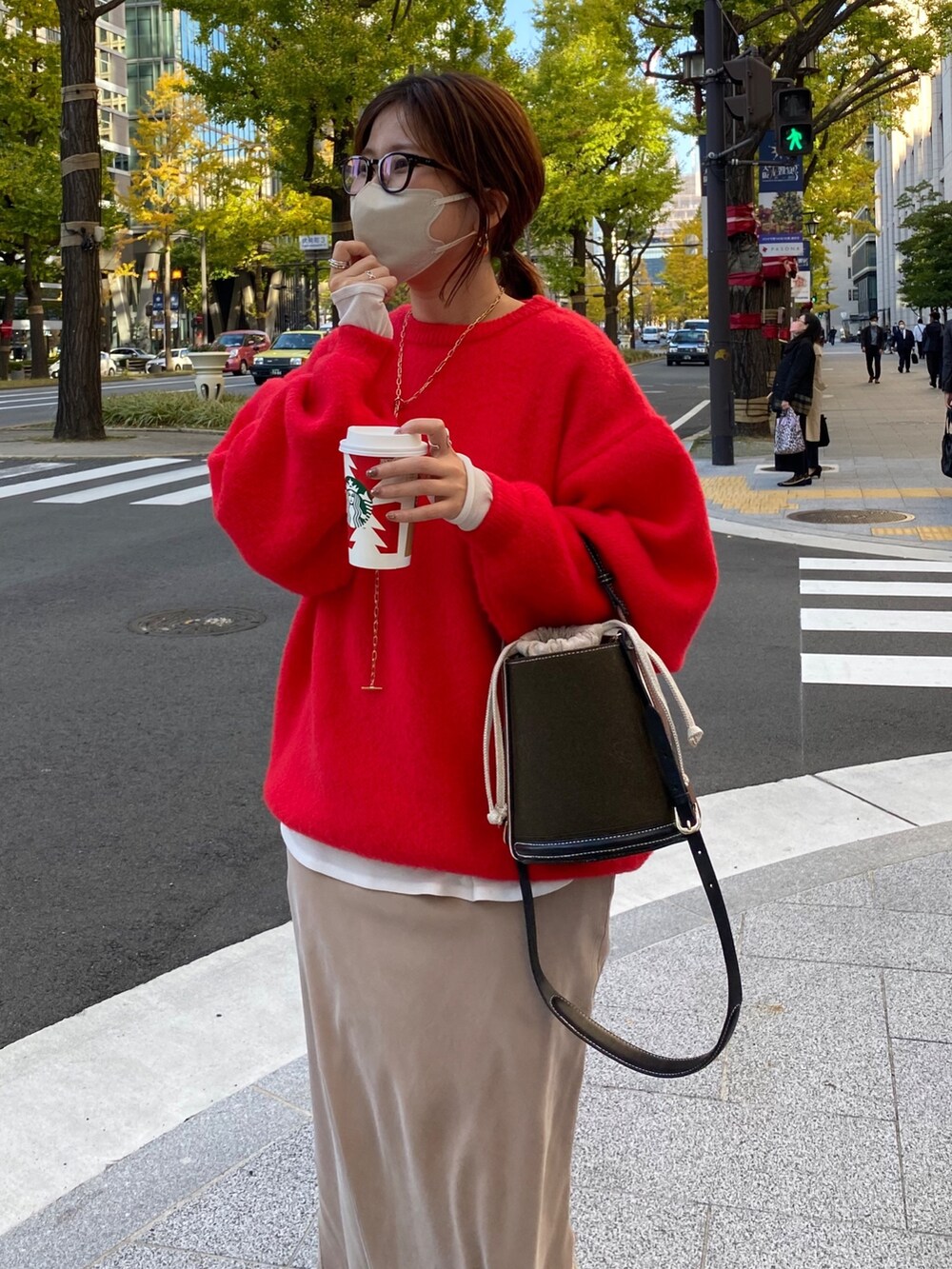 レッド系のニット/セーター、ホワイト系のTシャツ/カットソー、ベージュ系のスカートを着用したレディースの秋コーディネートの2枚目の写真