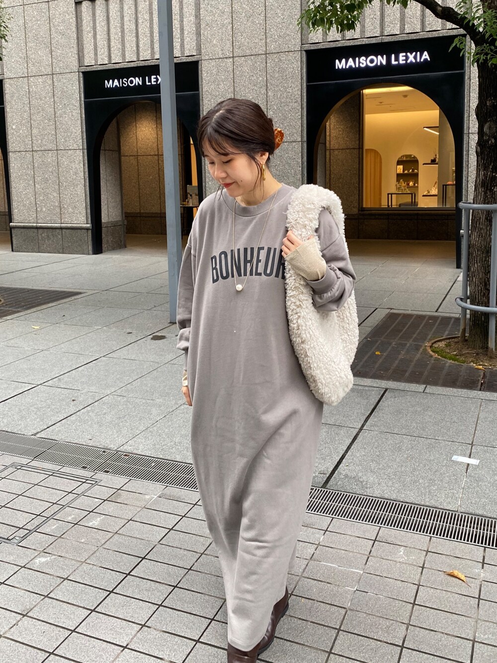 グレー系のワンピース、ブラウン系のブーツ、ゴールド系のTシャツ/カットソーを着用したレディースの秋コーディネートの2枚目の写真