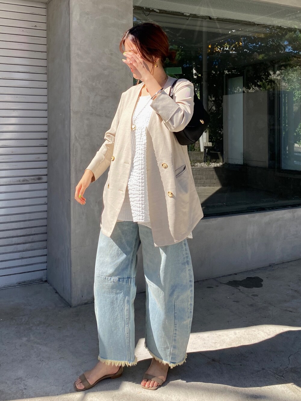 ホワイト系のキャミソール、ブルー系のデニムパンツ、ブラック系のショルダーバッグを着用したレディースの夏コーディネートの3枚目の写真