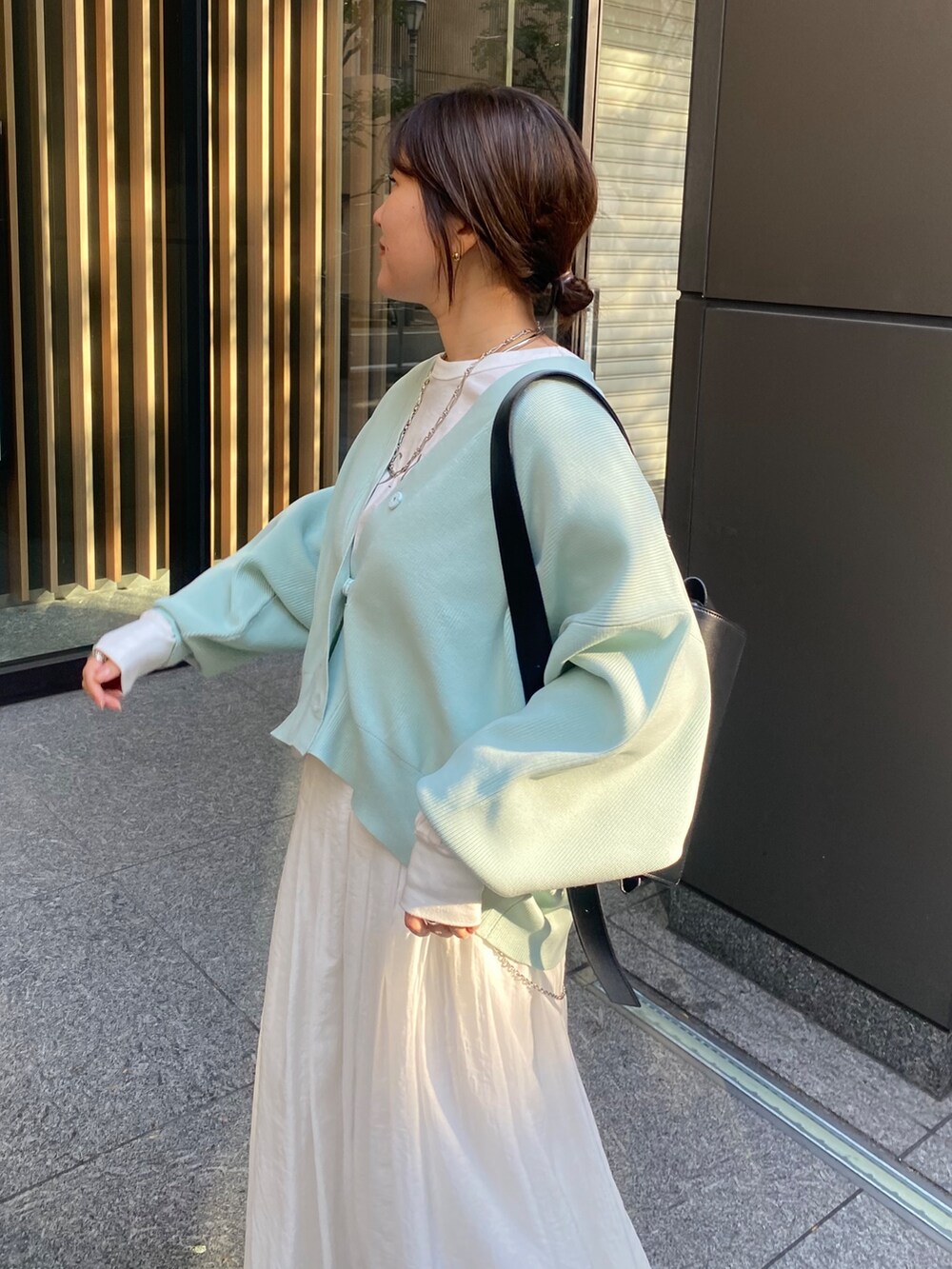 グリーン系のカーディガン/ボレロ、ホワイト系のスカートを着用したレディースの冬コーディネートの3枚目の写真