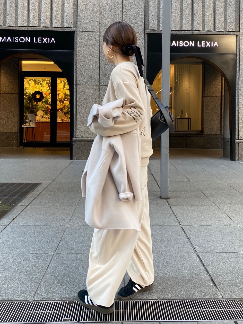 ホワイト系のその他アウター、ベージュ系のスラックス、ブラック系のショルダーバッグを着用したレディースの秋コーディネートの6枚目の写真