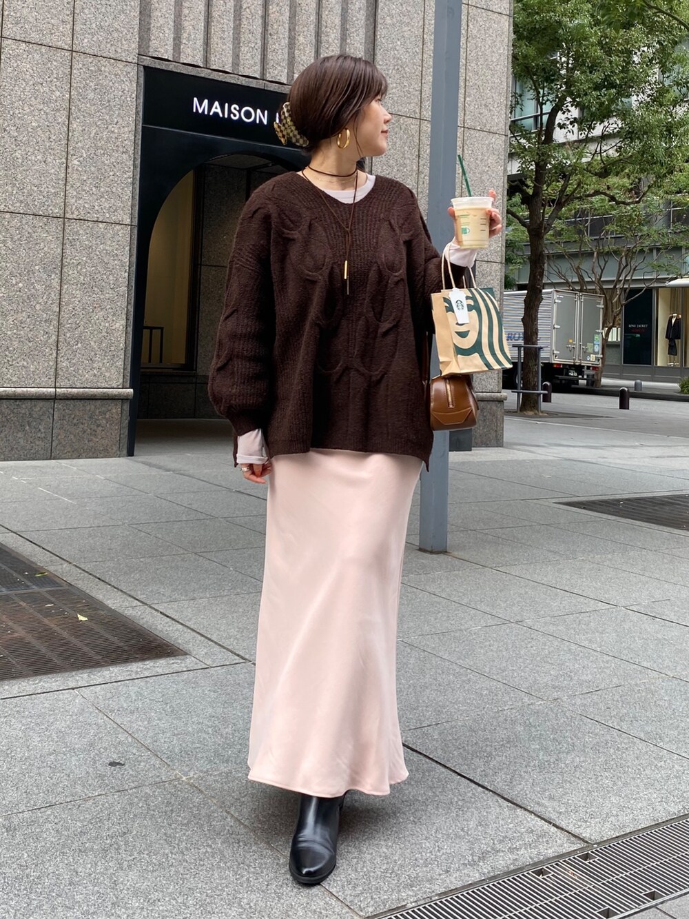 ブラウン系のニット/セーター、ピンク系のスカート、ブラック系のブーツを着用したレディースの冬コーディネートの3枚目の写真