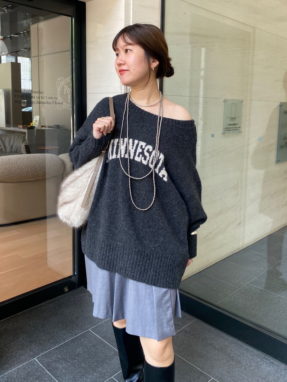 グレー系のニット/セーター、グレー系のスカート、ブラック系のブーツを着用したレディースの秋コーディネートの7枚目の写真