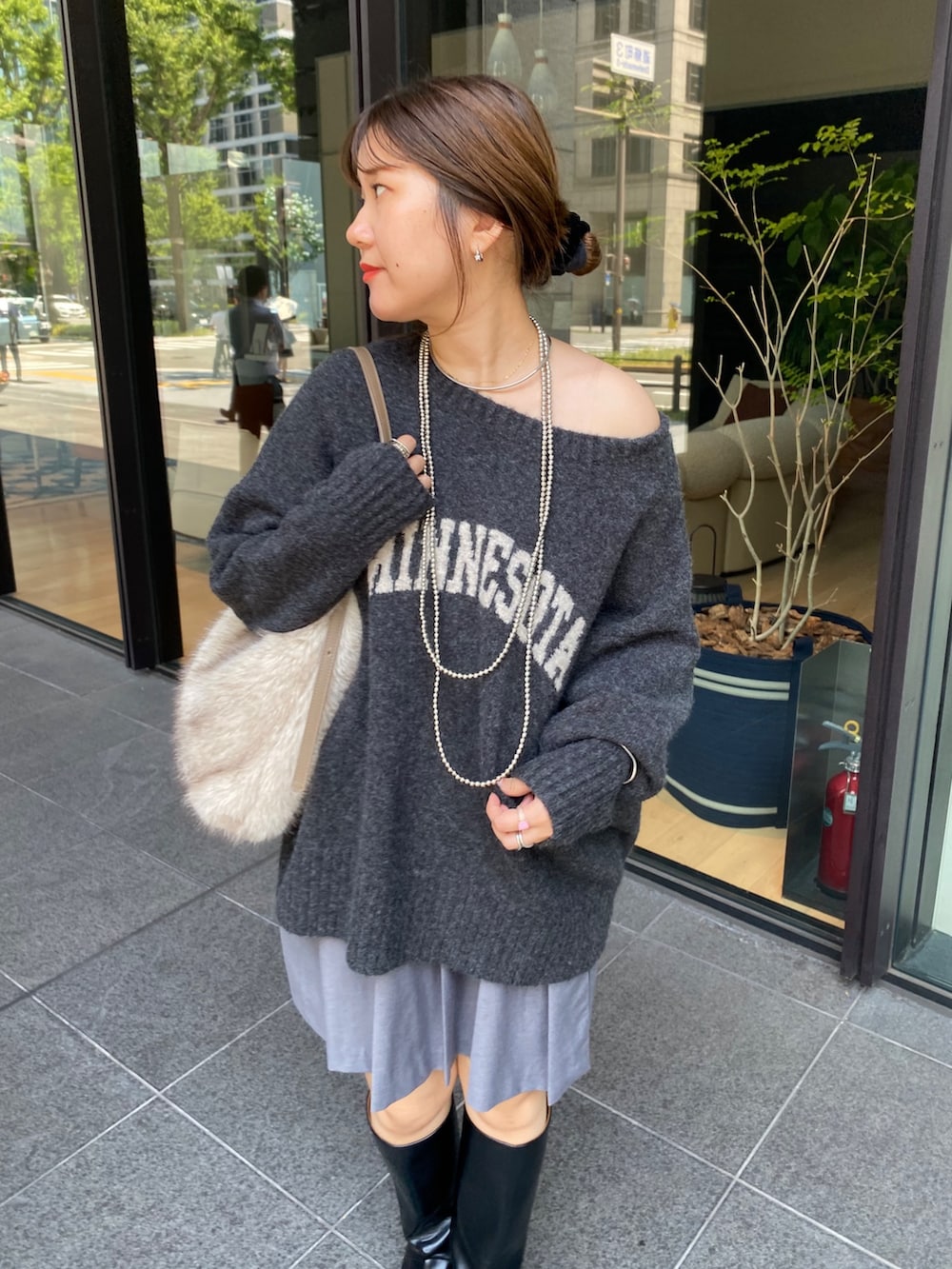 グレー系のニット/セーター、グレー系のスカート、ブラック系のブーツを着用したレディースの秋コーディネートの4枚目の写真