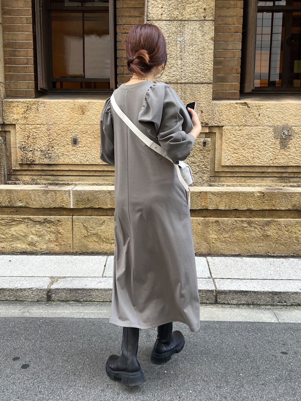 ブラウン系のワンピース、ホワイト系のショルダーバッグ、ブラック系のブーツを着用したレディースの秋コーディネートの3枚目の写真