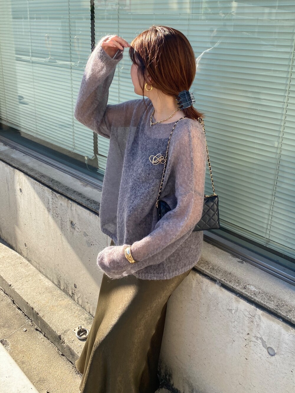 グレー系のニット/セーター、グリーン系のスカート、ゴールド系のブローチ/コサージュを着用したレディースの秋コーディネートの7枚目の写真