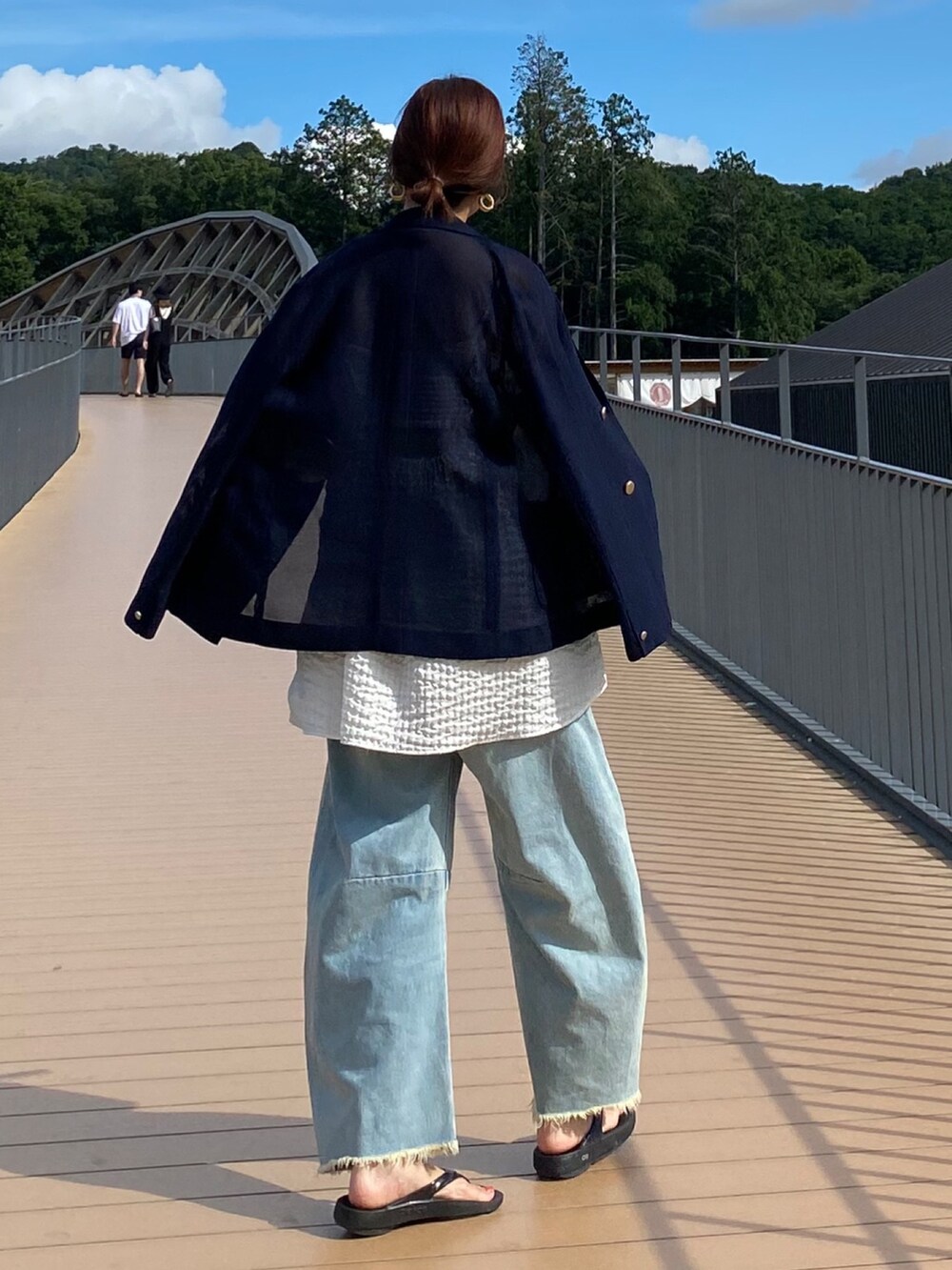 ブルー系のテーラードジャケット、ホワイト系のキャミソール、ブルー系のデニムパンツを着用したレディースの夏コーディネートの10枚目の写真