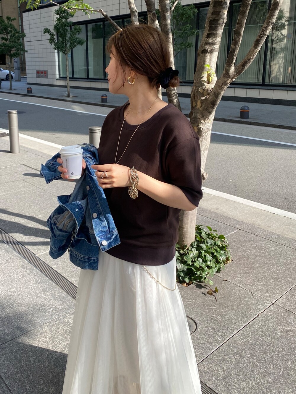 ブラウン系のスウェット、ホワイト系のスカート、ブルー系のデニムジャケットを着用したレディースの春コーディネートの2枚目の写真