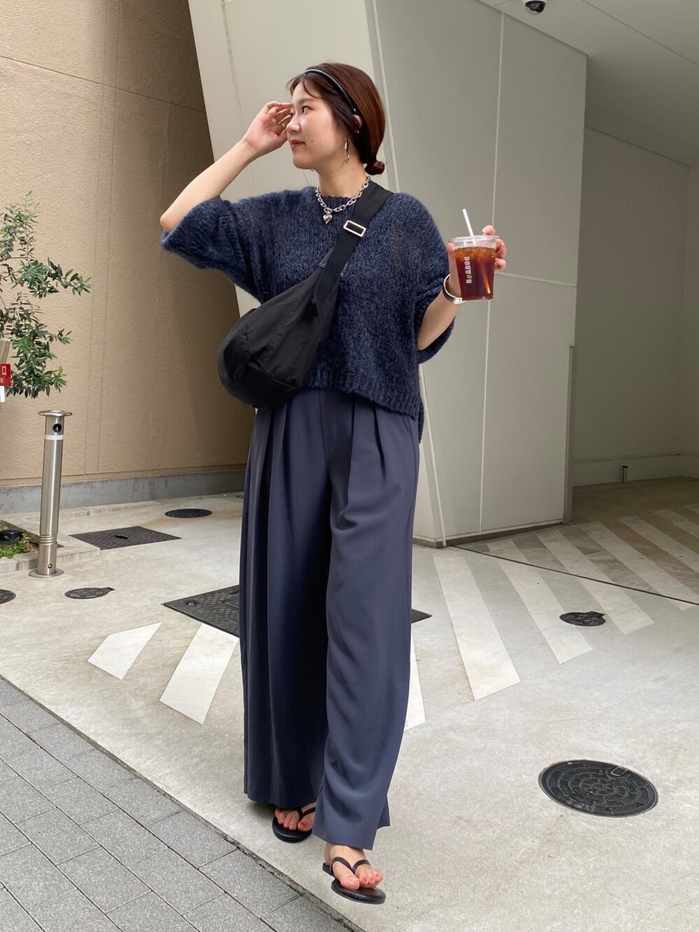 グレー系のニット/セーター、グレー系のスラックス、ブラック系のショルダーバッグを着用したレディースの秋コーディネートの2枚目の写真