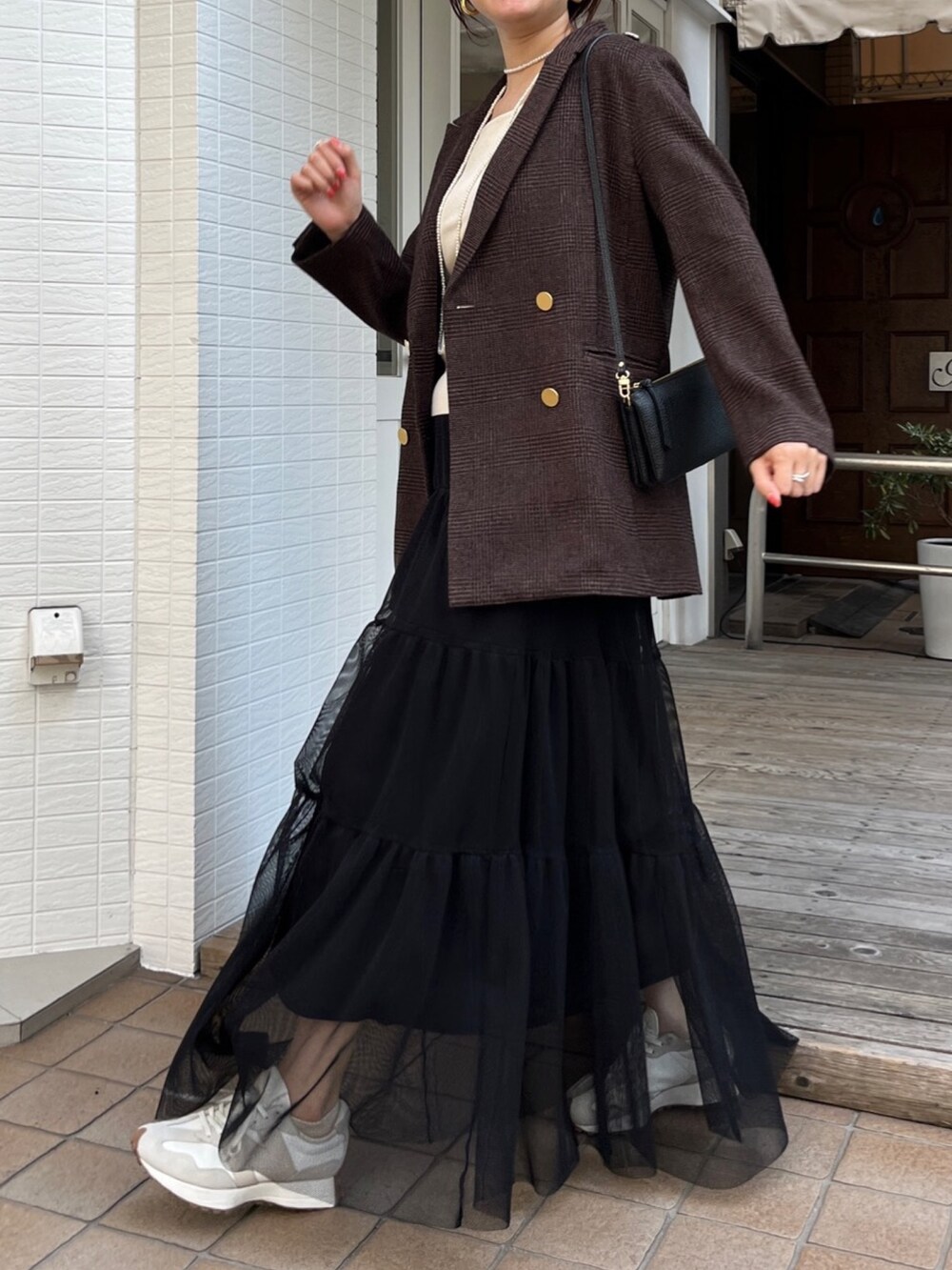 ブラウン系のテーラードジャケット、ブラック系のスカート、ブラック系のショルダーバッグを着用したレディースの秋コーディネートの9枚目の写真