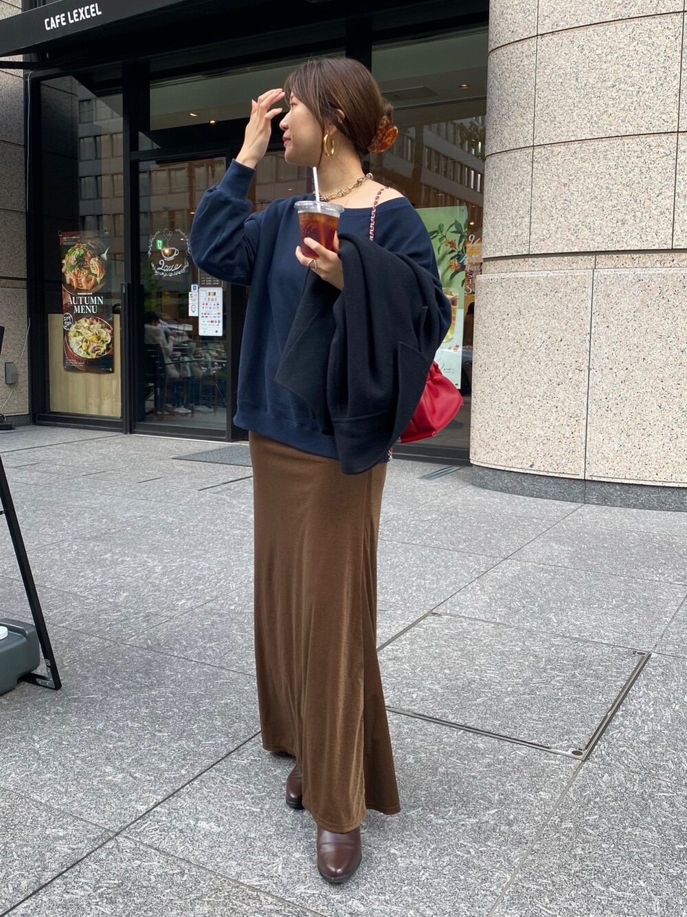 ブルー系のスウェット、ブラウン系のブーツ、レッド系のショルダーバッグを着用したレディースの秋コーディネートの2枚目の写真