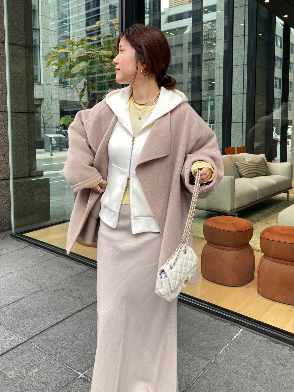 グレー系のパーカー、ブラック系のスカート、ホワイト系のショルダーバッグを着用したレディースの春コーディネートの2枚目の写真