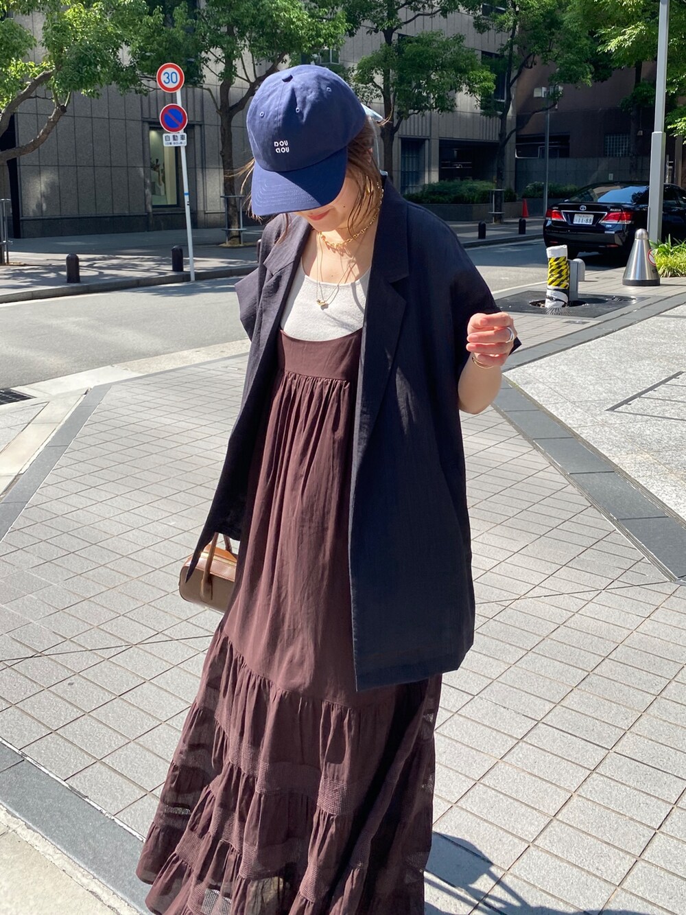 グレー系のテーラードジャケット、ブラウン系のワンピース、ブルー系のキャップを着用したレディースの夏コーディネートの6枚目の写真