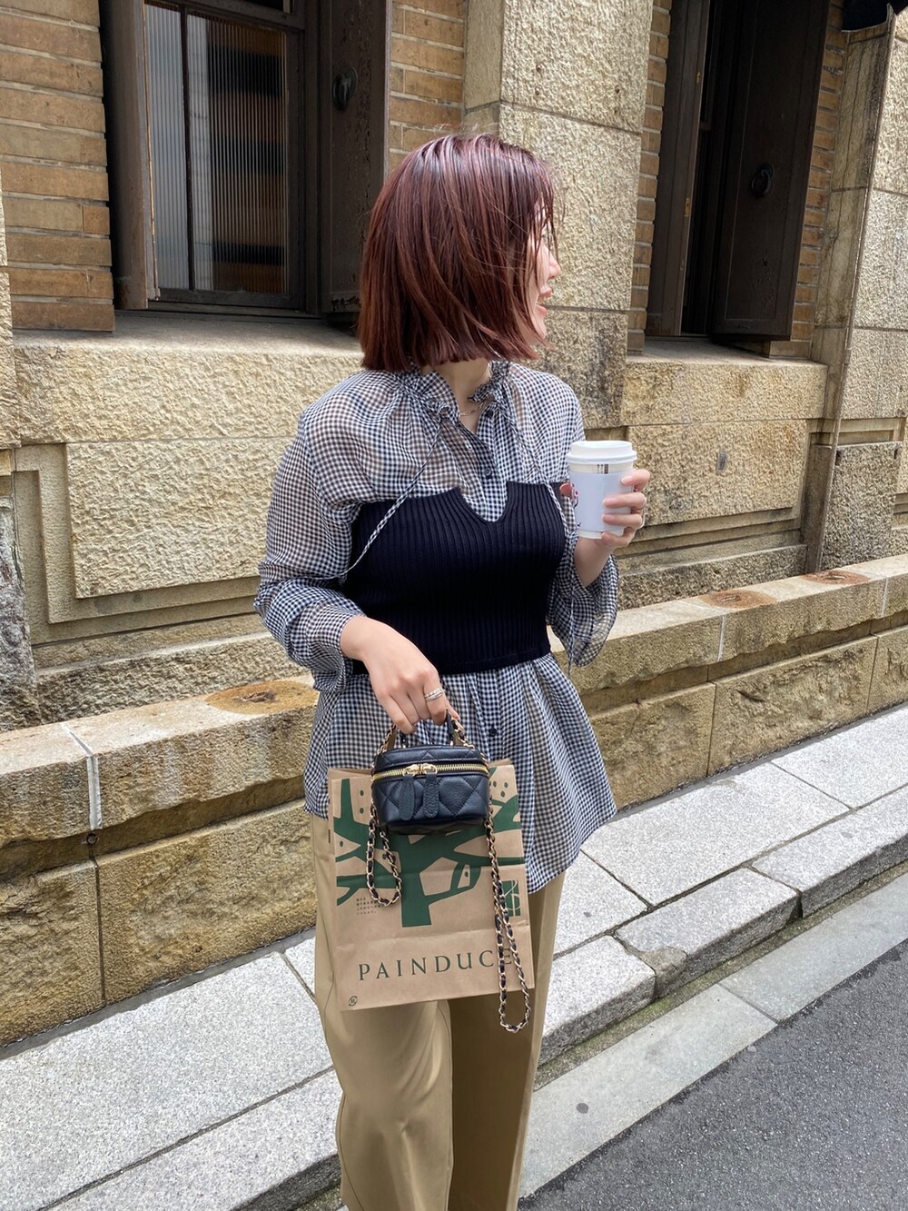 ブラック系のニット/セーター、ブラック系のシャツ/ブラウス、ベージュ系のチノパンツを着用したレディースの春コーディネートの7枚目の写真