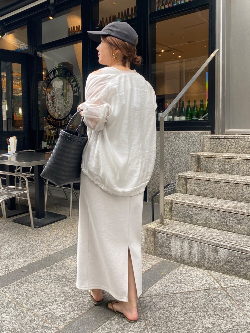 ベージュ系のワンピース、ホワイト系のブルゾン、ブラック系のかごバッグを着用したレディースの春コーディネートの2枚目の写真