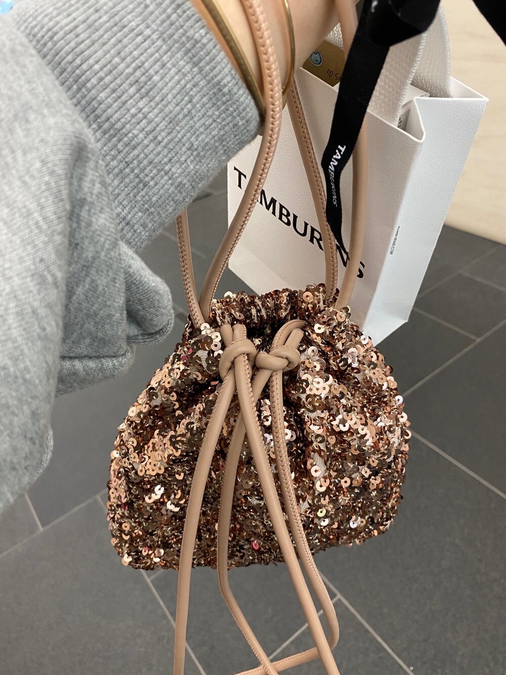 グレー系のスウェット、ブラック系のスカート、ピンク系のハンドバッグを着用したレディースの秋コーディネートの8枚目の写真