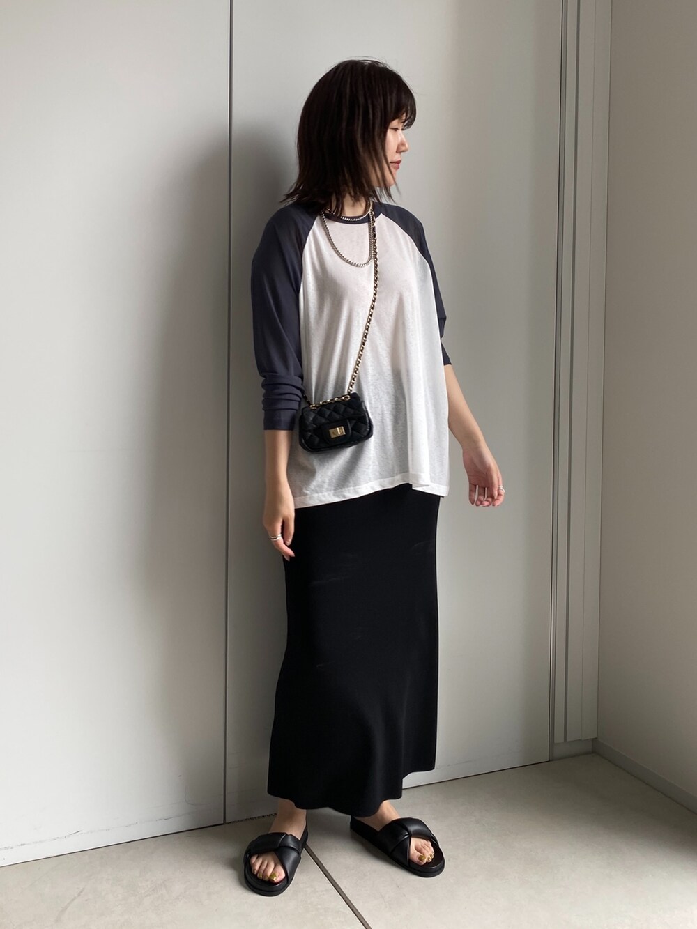 ホワイト系のTシャツ/カットソー、ブラック系のスカート、ブラック系のショルダーバッグを着用したレディースの夏コーディネートの3枚目の写真