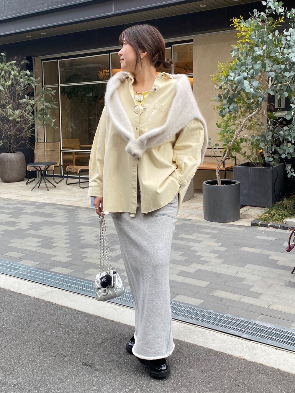 イエロー系のシャツ/ブラウス、グレー系のスカート、イエロー系のタンクトップを着用したレディースの冬コーディネートの4枚目の写真